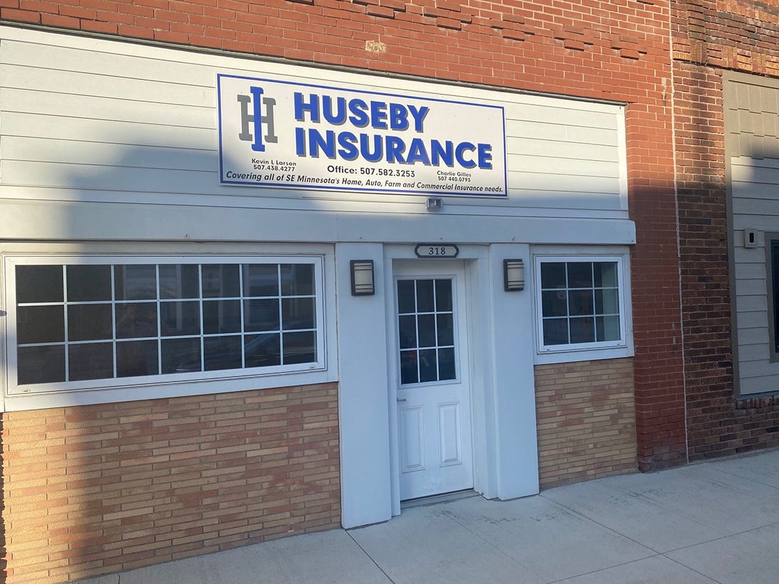 About Our Agency - Exterior View of the Huseby Insurance Office Building Along Main Street at Sunset with a Logo Sign Above the Front Door