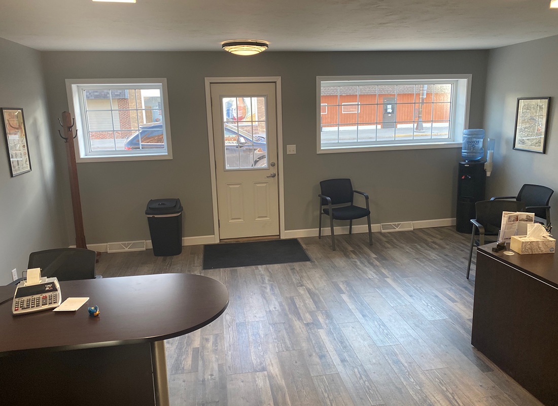 Contact - View of the Front Door Entrance and Two Desks at the Huseby Insurance Office with Wooden Floors and Grey Walls