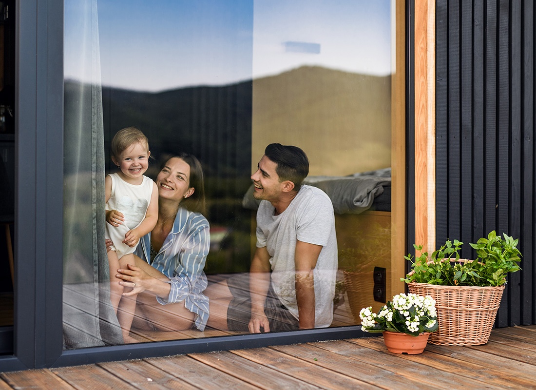Personal Insurance - View of Cheerful Parents Playing with Their Toddler at Home While Sitting in Front of the Back Patio Full Length Windows